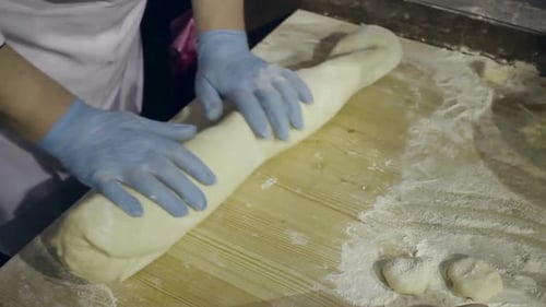 Baker Shaping Dough on Wooden Board in Kitchen