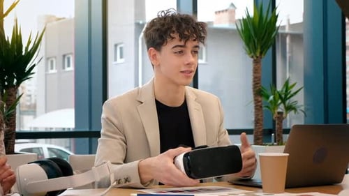 Business conference in VR in an office. A young man explaining others how to use VR glasses, gadgets