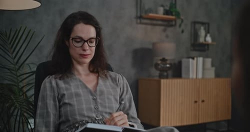 Professional Female Therapist Talks Takes Notes During Therapy for Child