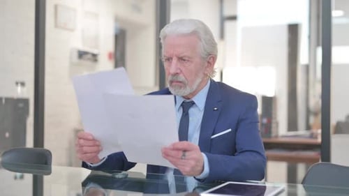 Senior Man Reviews Documents in Conference Room