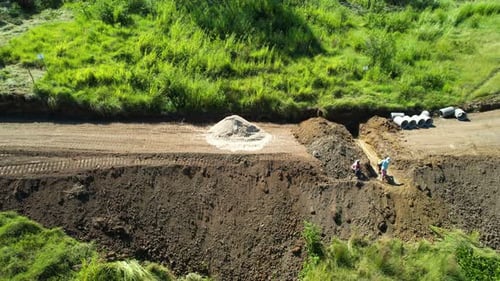 Vista aérea de la carretera en construcción en los suburbios con trabajadores cavando al mediodía