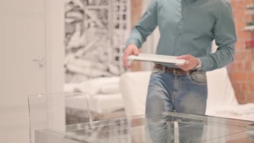 Man Opens Laptop at Glass Table in Home