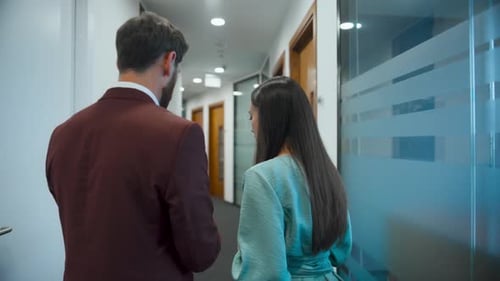 Rear View Business Couple Walking in Coworking Center. Involved Colleagues Discussing New