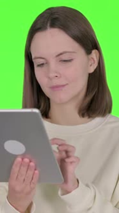 Young Woman using Digital Tablet on Green Background, vertical video