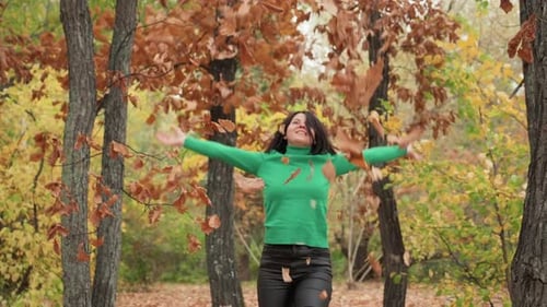 Woman Throws Leaves in Autumn Forest Scene