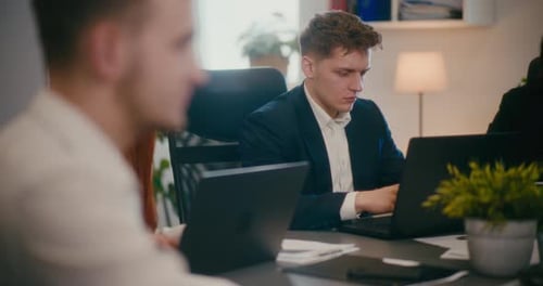Businessman Working on Laptop at Desk in Office