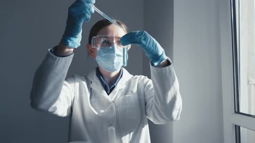 Female Scientist Analyzing Test Tube With Pipette
