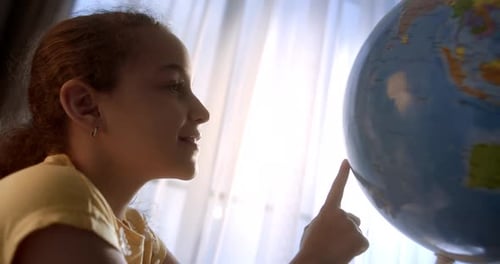 Girl Looks at Globe by Sunny Window