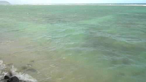 Las olas turquesas del océano salpican la costa tropical de arena y rocas. Olas espumosas en una victoria