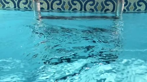 Transparente Nahaufnahme von Schwimmbadleitern unter durchsichtigem, kristallklarem, reinfließendem Wasser