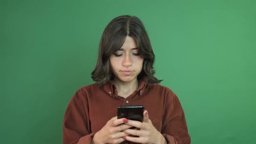 Young Woman Uses Smartphone Against Green Background