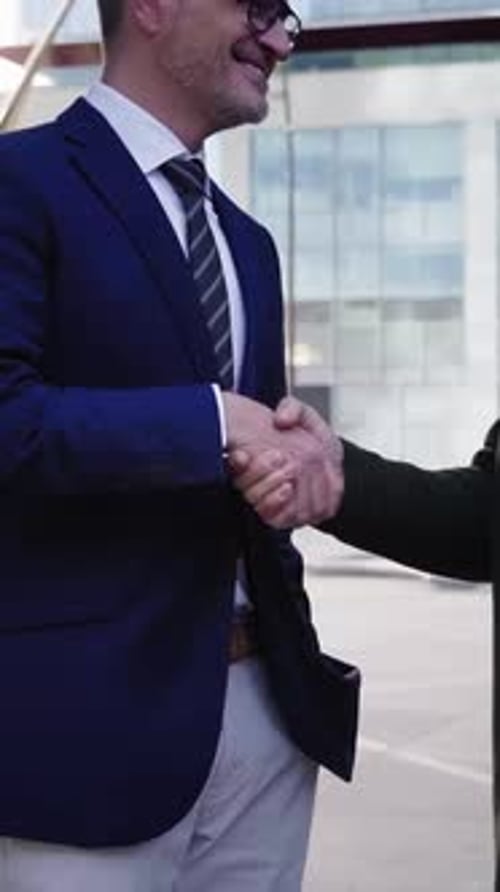 Dois empresários caucasianos fechando um negócio com um aperto de mão sorrindo