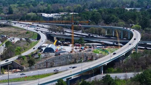 Interstate traffic and elevated highway during sunny day in Atlanta Suburb. Aerial wide shot. Yellow