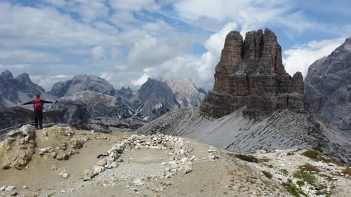 A hiker standing alone in the mountains and celebrating an adventurous and successful hike in the Do