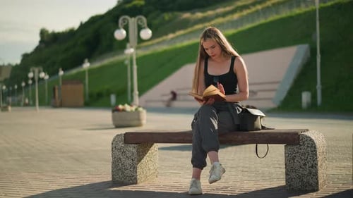 Woman Reading on Bench in Urban Park