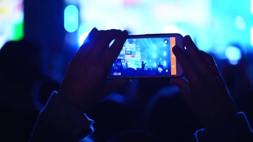 Close Up of Person Hands Silhouette Taking Photo or Recording Video of Live Music Concert with
