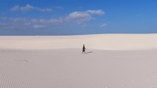 A Solitary Figure Traverses Vast Sand Dunes Under a Clear Blue Sky on Socotra Island
