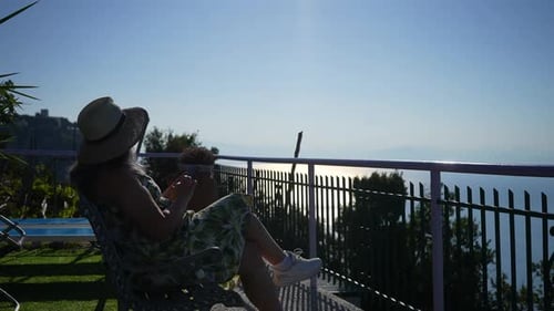 Silhouette of Female Tourist in Hat and Sunglasses Using Phone in Amalfi Coast Taking Photo Shooting