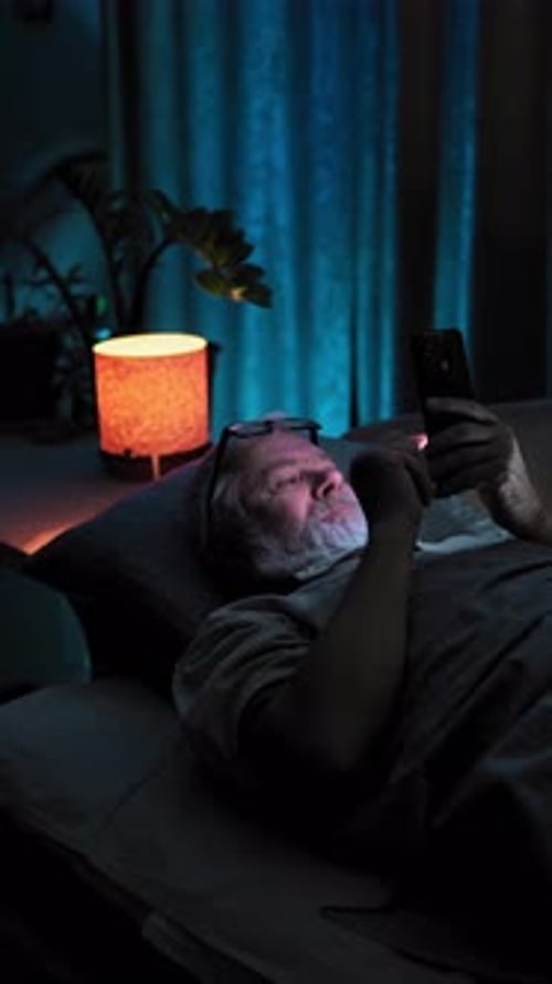 Elderly Man Laying in Bed and Very Emotion React to Video Content on His Phone