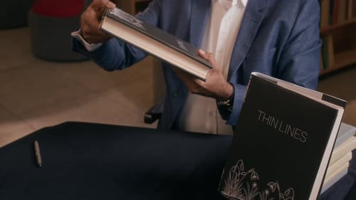 Unrecognizable Man Selling Copies of his Books at Table in Book Store