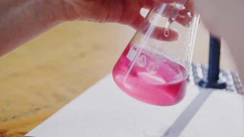 Gros plan d'un tube en verre avec du liquide cramoisi dans la main d'un scientifique pendant un test médical