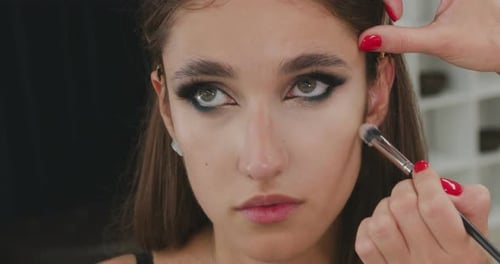 Closeup Shot of a Makeup Artist Applying Concealer Under the Client Eyes with a Brush Dramatic