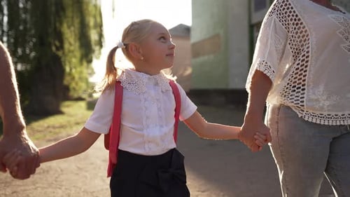 Colegiala camina a la escuela con sus padres