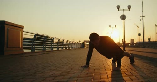 Young Athletic Man Works Out Doing Pushups on a City Street at Sunset