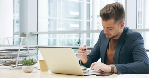 4k video footage of a handsome young businessman working on his laptop in the office