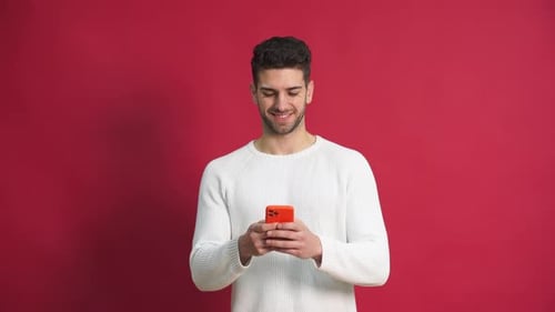 Young Adult Using Smartphone on Red Background