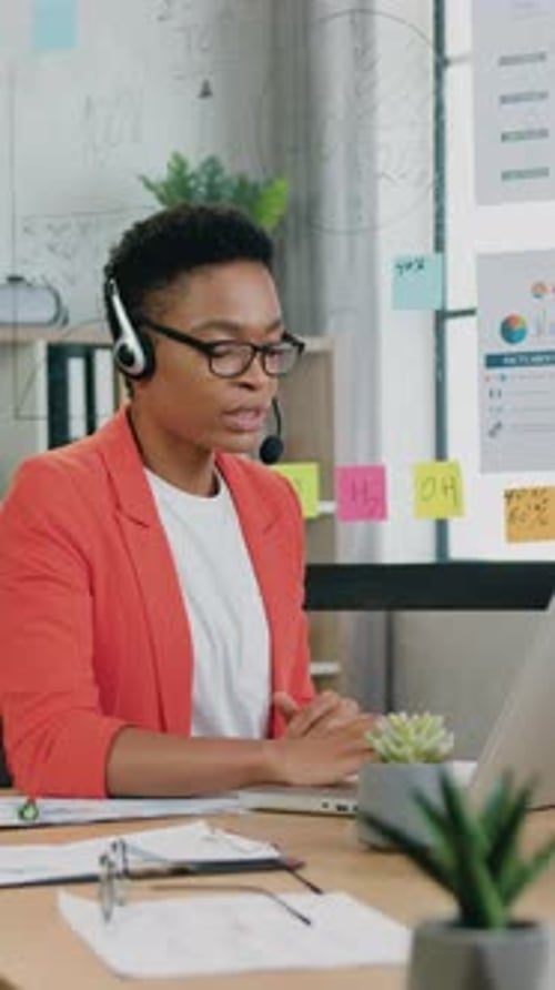 Woman Talking on Headset at Desk with Laptop