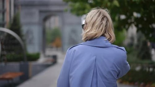 Woman with Blonde Hair Walks Down Sidewalk