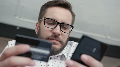 Man Using Online Banking with Smart Phone and Card