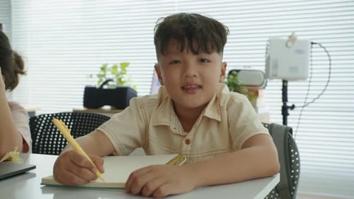 Boy Sits and Writes in His Notebook