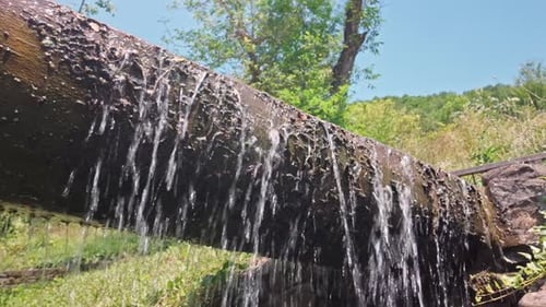 Overflowing water cascading from rustic wooden sluice log flume chute