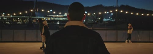 Vidéo arrière d'un jeune homme portant des patins sur une piste de patinage en soirée Un gars regardant une merveilleuse soirée