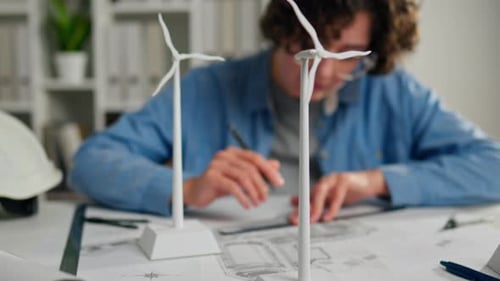 Young engineer designing sustainable wind turbine models in an office workspace