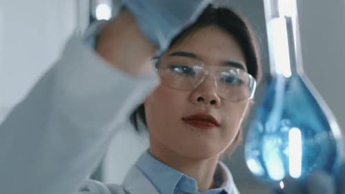 Young Scientist Analyzing Blue Liquid in Laboratory