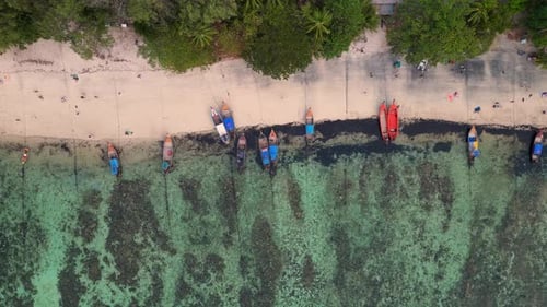 bunte Boote, die am Strand der Riffinsel festgemacht haben. Atemberaubende Flugdrohne
aus der Luft