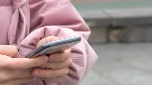 Detail of a hand holding a mobile and sending a message. Holding a smartphone. Close up.