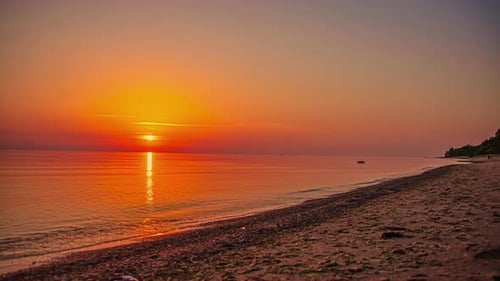 A dreamy golden sunset reflecting off the glassy surface of the ocean - beach time lapse