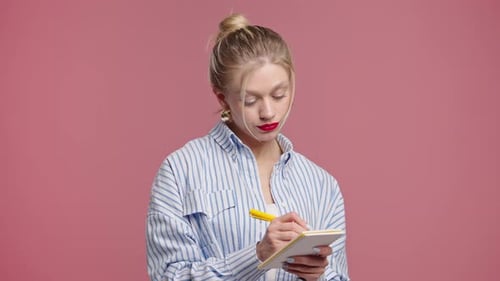 Thoughtful Woman Writing Notes With Pen in Studio