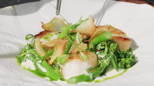 Scallops being decorated for serving with tweezers