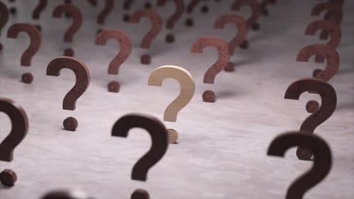 El único signo de interrogación de madera de color claro se destaca entre una multitud de signos oscuros que simbolizan