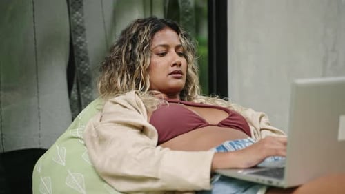 Relaxed Multiethnic Woman Works on Laptop Poolside Achieving Worklife Balance Comfortable Outdoor