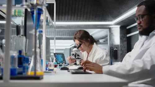 Scientists Working with Microscope and Typing in Lab