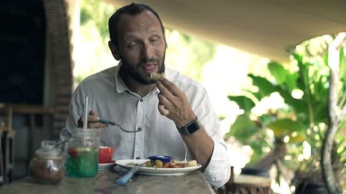 Young, Happy Man Eating Meal and Drinking Beverage Sitting in Cafe 30s