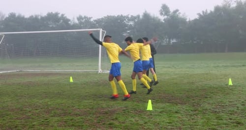 Soccer players practicing drills on field with coach observing and guiding