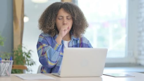 Woman Working at Desk Coughs into Hand