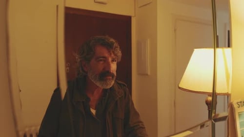Man Adjusts Himself in Mirror in Bright Room